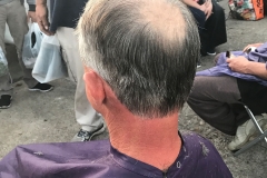 A homeless man almost done with his haircut.