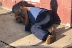 A homeless man lays on the sidewalk downtown. We got a chance to feed him.