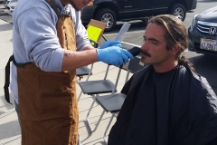 Streets of Hope San Diego volunteer trimming a homeless man's goatee