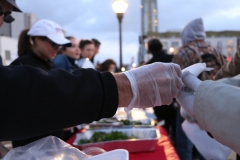 A gloved Streets of Hope volunteer passes out food to the homeless on Easter.