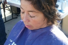 A homeless woman enjoys her hair cut.