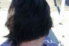 A homeless woman hair cut view from the back.