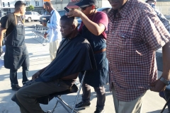 A homeless black man gets his hair cut downtown.