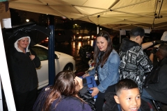 Tammy cuts a homeless girls hair while her mother looks on and smiles.