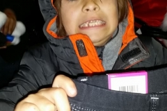 A little homeless girl hold up her new jeans after opening her Christmas gifts.