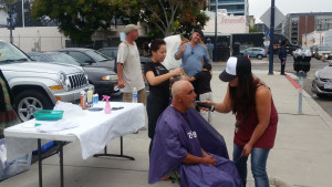 Eric waving while Tammy trims a San Diego homeless man's beard